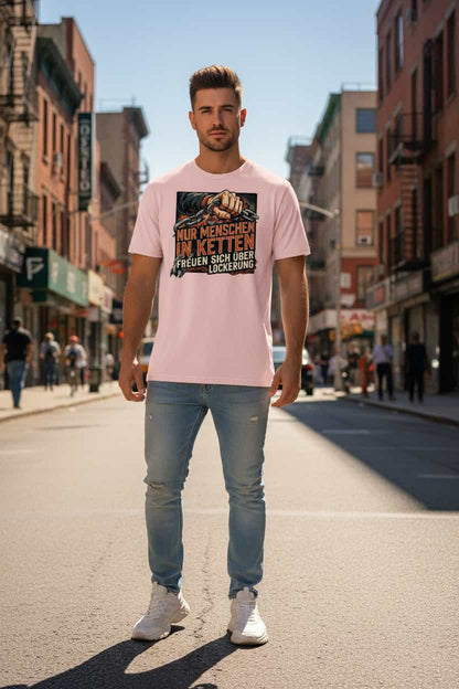 Herren Bio-Baumwolle T-Shirt in Cotton Pink mit Statement-Print "Nur Menschen in Ketten freuen sich über Lockerung" – männlicher Model trägt das Shirt in urbaner Stadtkulisse bei strahlendem Sonnenschein und blauem Himmel – GOTS-zertifiziert, nachhaltige Streetwear von TextilRebell